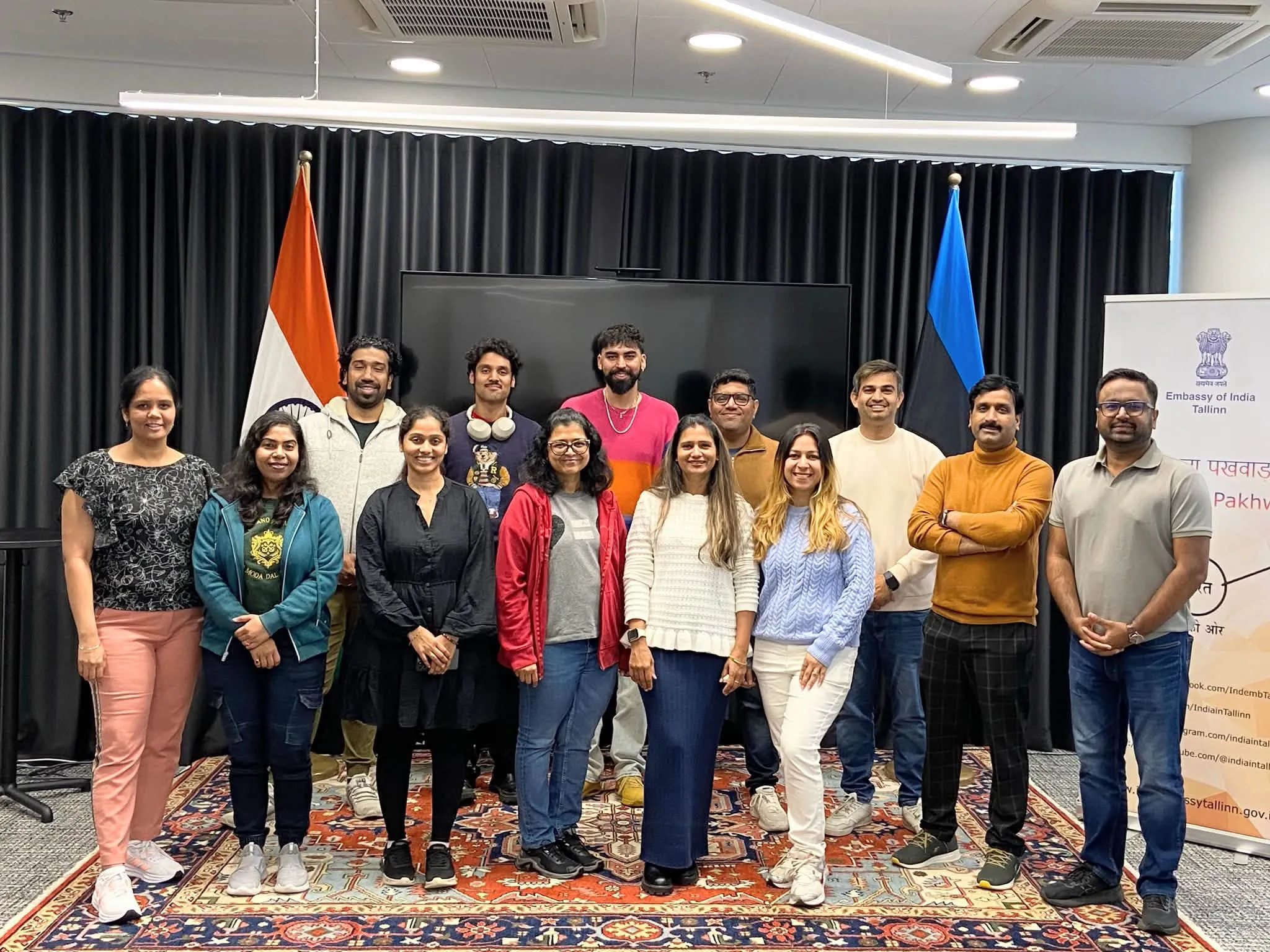 IAE members standing together for a group photo at the Embassy of India, Tallinn, between the Indian and Estonian flags