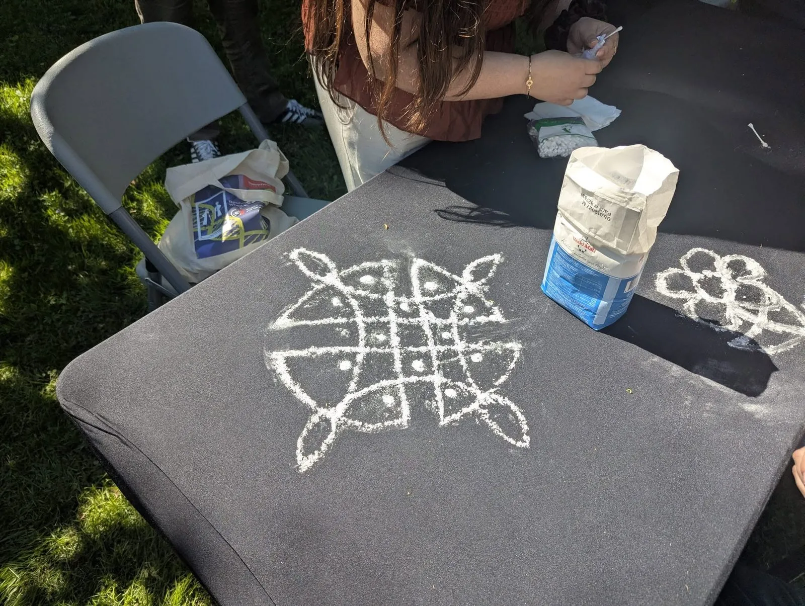 Valge pulbriga tumedale lauale joonistatud rangoli muster